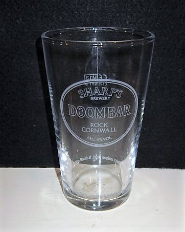 beer glass from the Sharp's brewery in England with the inscription 'Sharp's Brewery Doombar Rock Cornwall Alc 4% VOL Narural Ingredients Cornish Water, English Malted Barley, Whole Hop Flowers And Sharp's unique Yeast '